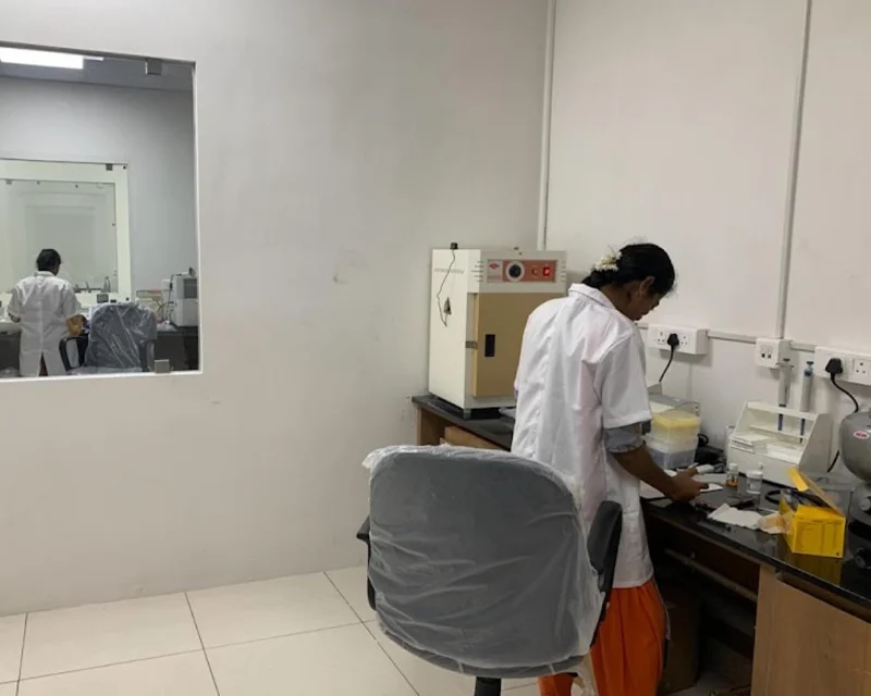 Technician working at a sample preparation bench beside a hot air oven